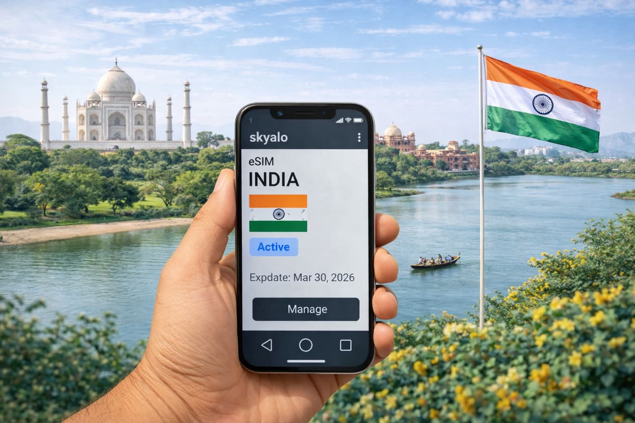 Chytrý telefon s aktivovanou eSIM India v aplikaci Skyalo na pozadí Tádž Mahalu, řeky a indické vlajky za slunečného dne.