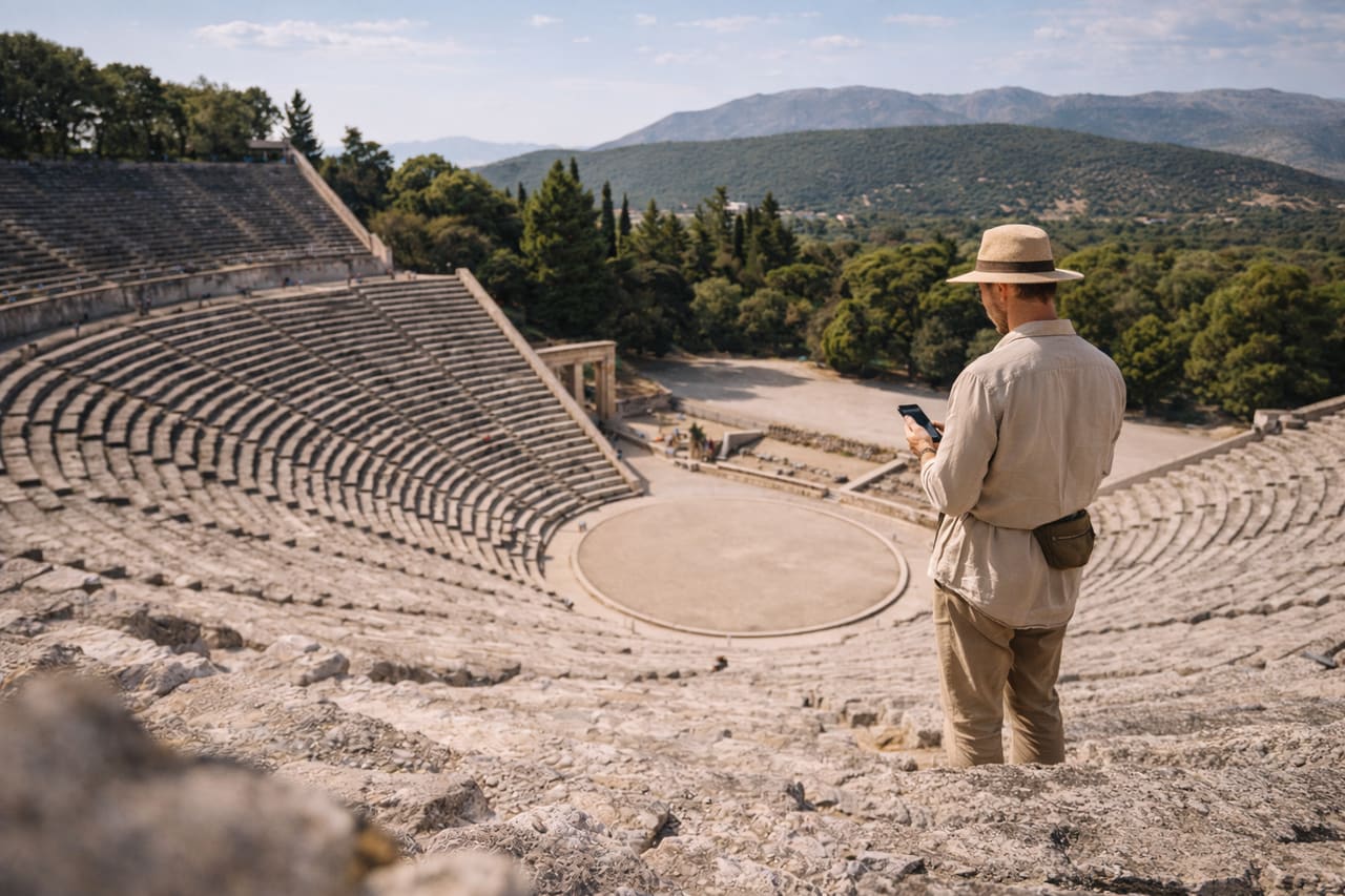 Antico teatro di Epidauro tra colline verdi e un visitatore con smartphone con eSIM attiva